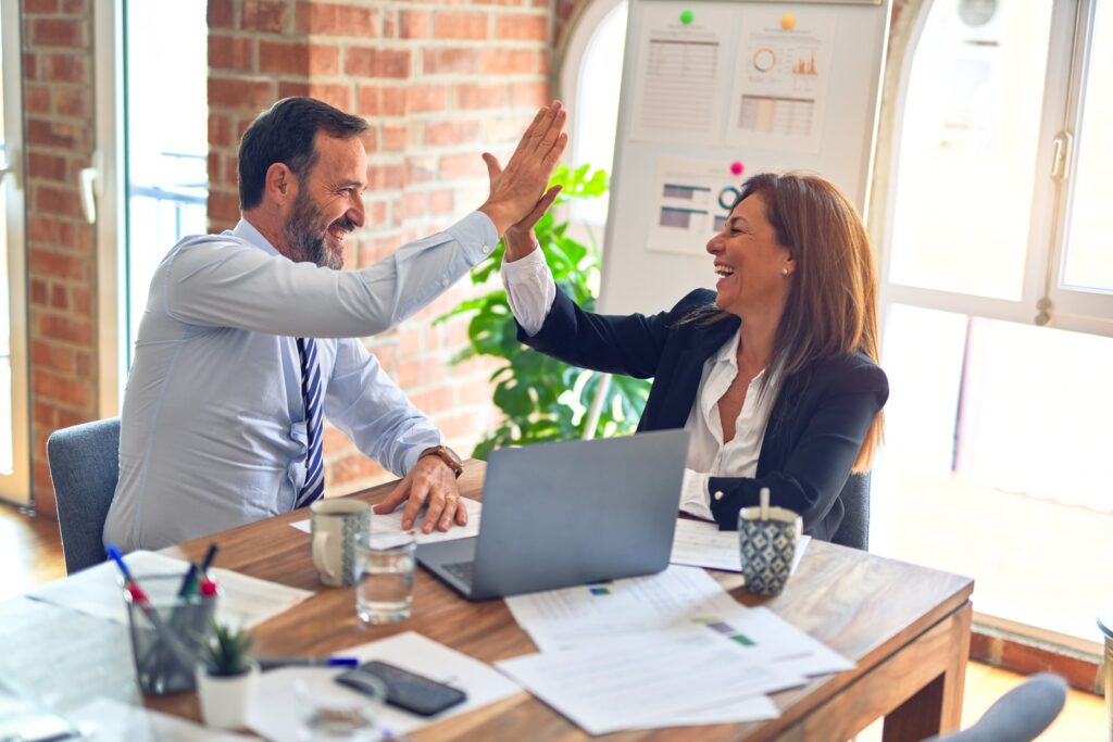 Business people share a High Five over a laptop